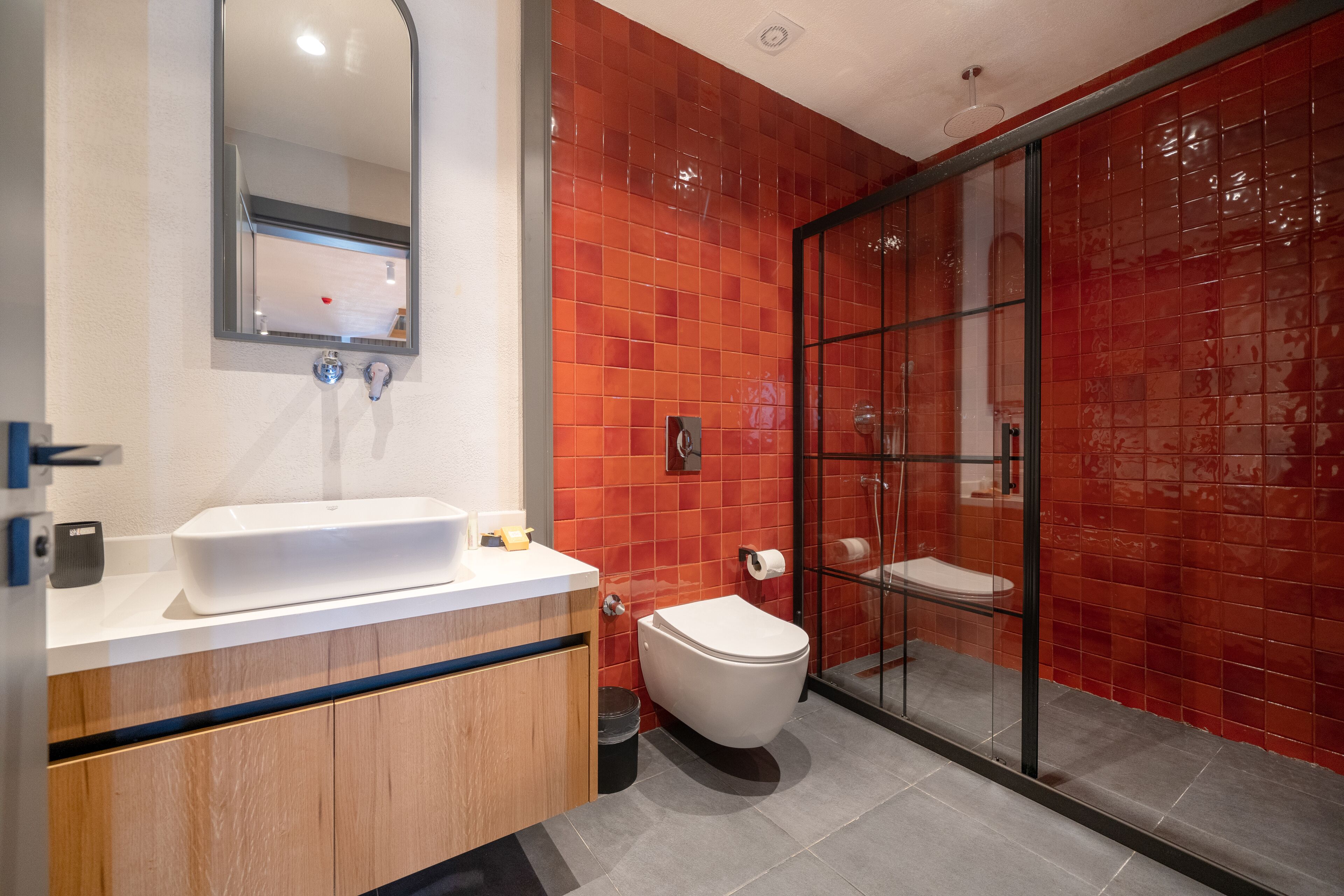 Un baño moderno con un lavamanos blanco, un inodoro y una cabina de ducha de vidrio.