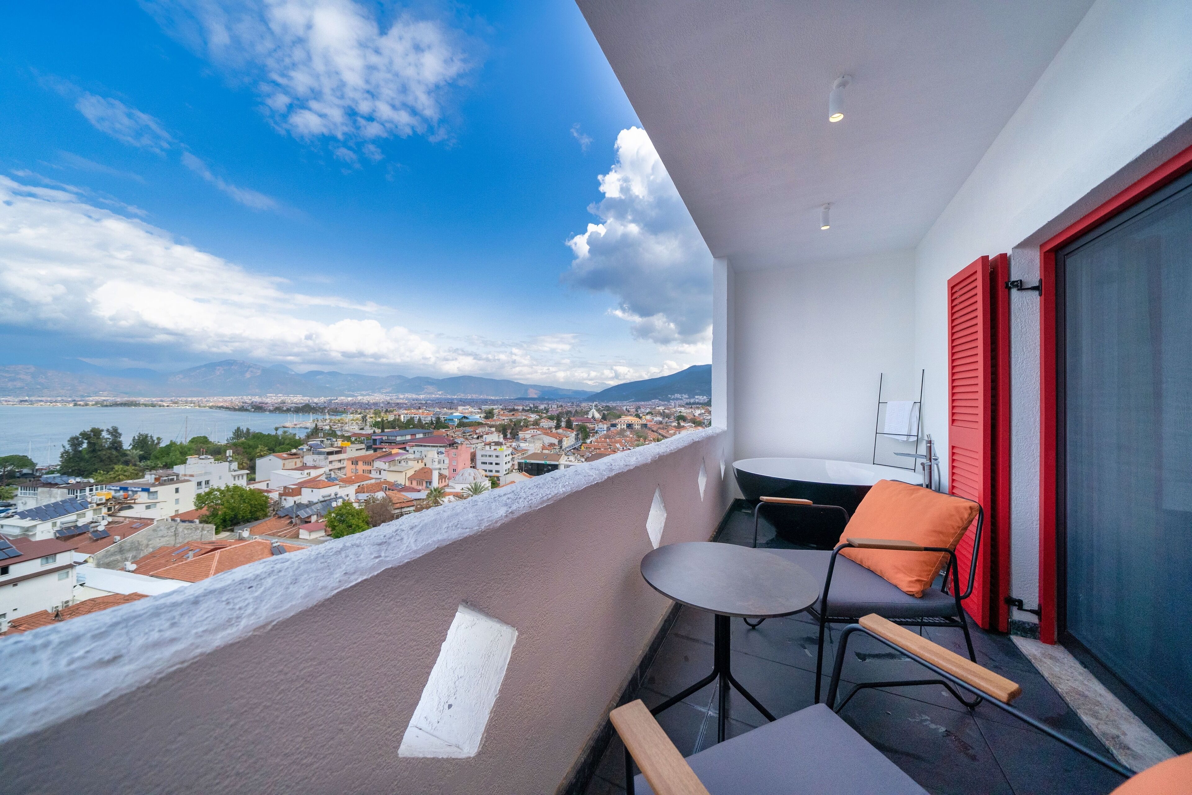 Ein Balkon mit Blick auf eine Stadtlandschaft, einem Tisch und zwei Stühlen.