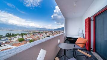 Ein Balkon mit Blick auf eine Stadtlandschaft, einem Tisch und zwei Stühlen.