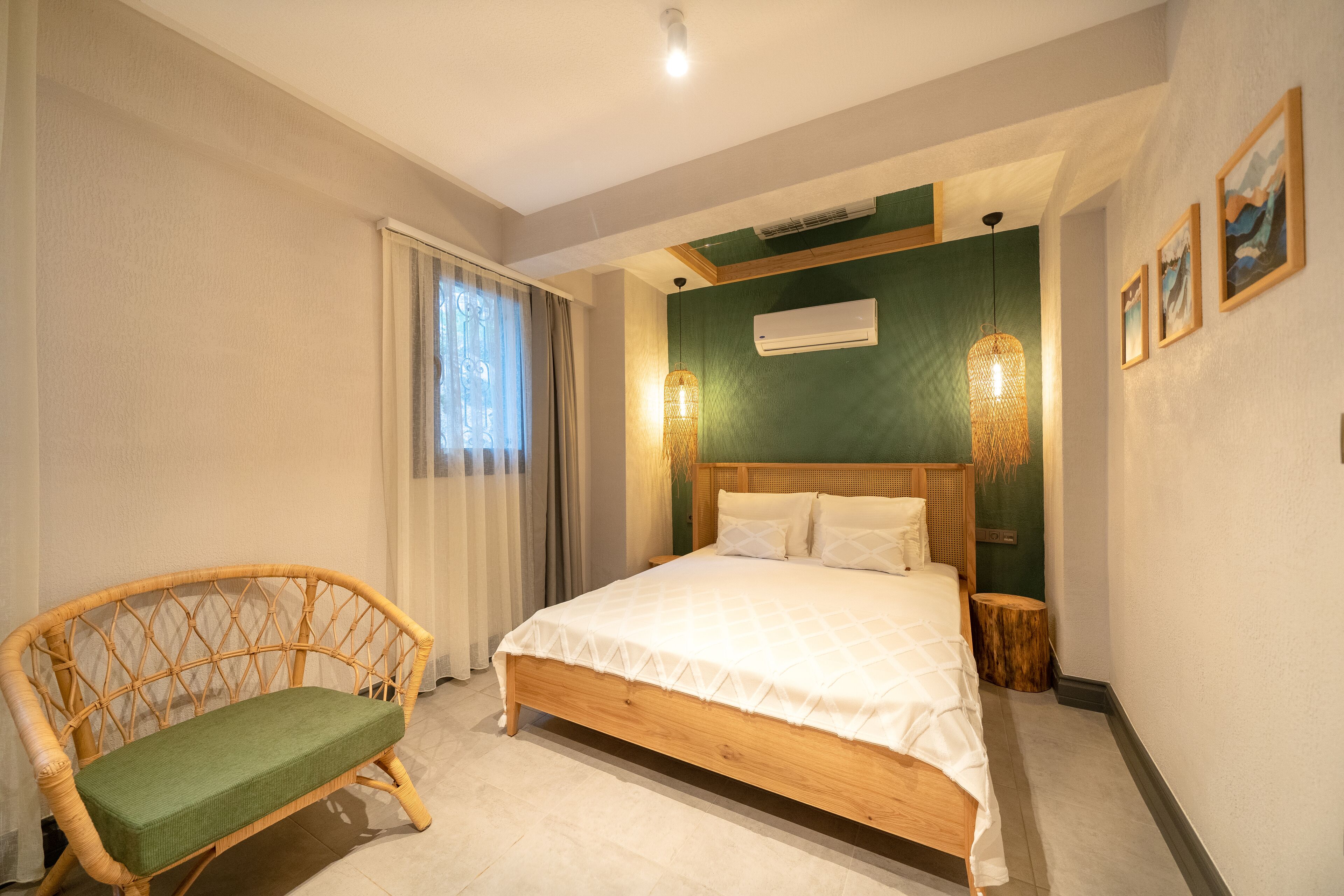 A bedroom with a wooden bed, a wicker chair, a green wall, and a window with curtains.