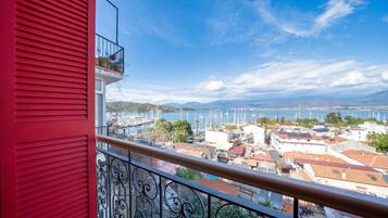 Ein Balkon mit roter Wand, der auf einen Yachthafen mit Booten und Gebäuden blickt.
