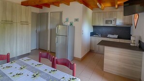 A compact kitchen with a microwave, refrigerator, and wooden cabinets.