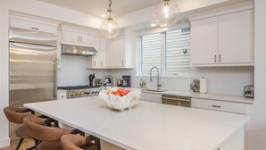 A modern kitchen with white cabinets, stainless steel appliances, and a large island with bar stools. - Luxury condo w/private hot tub & Lone Peak Views, minutes to Big Sky Resort - Copper John Getaway (Big Sky)