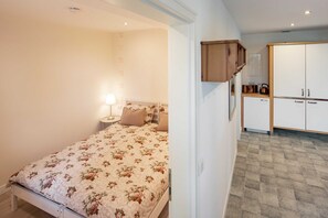 A bedroom with a floral bedspread, a bedside lamp, and a wardrobe with a mirror.