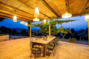 Un espace de restauration en plein air avec une table et des chaises en bois, entouré d’une pergola couverte de plantes grimpantes.