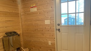 Ein Zimmer mit Holzwänden, einer weißen Tür, einem Harvia Geschirrspüler und einem Fenster mit Blick auf Häuser.