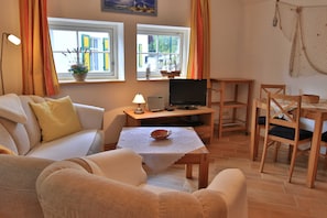 A cozy living room with a sofa, a table with a bowl, a TV, and a window with curtains. - Ole Koot Vacation Home - Fischerkate Freest (Kroeslin)