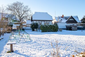 A snow-covered outdoor area with a playground structure, a bench, and a building labeled 'FISCHERKATE.' - Vacation Apartment on Rügen - Fischerkate Freest (Kröslin)