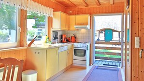 Un interior de madera con cocina, mesa de comedor y vistas al exterior.