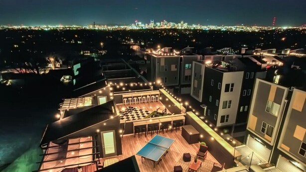 A rooftop terrace with a ping pong table, seating area, and a view of the cityscape at night. - Elvis`s Rooftop - Brand New Nashville Hang Out (Nashville)