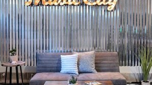 A modern living room with a sofa, coffee table, and decorative pillows. A vertical wooden panel with the words "Music City" is in the background. - Elvis`s Rooftop - Brand New Nashville Hang Out (Nashville)