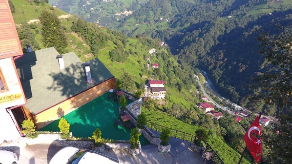 Un paisaje montañoso con una zona de piscina, un letrero de restaurante y una bandera.