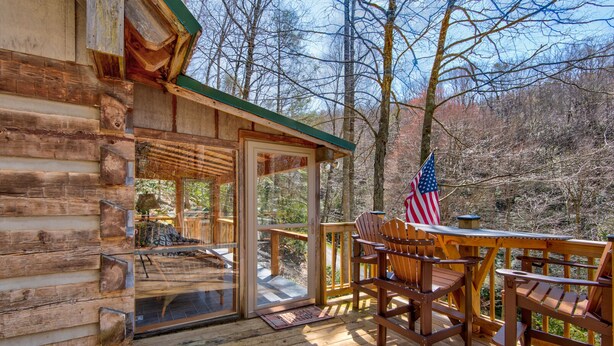Une cabane en bois dotée d’une terrasse, de chaises en bois et d’un drapeau américain.