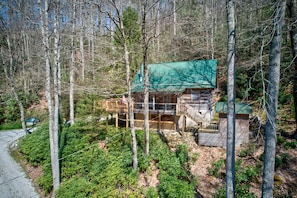 Une cabane avec un toit végétalisé, une terrasse en bois et un petit porche.