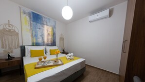 Ein Hotelzimmer mit einem Bett, Nachttischen, einem großen abstrakten Gemälde, einer Klimaanlage und einem Holzboden.