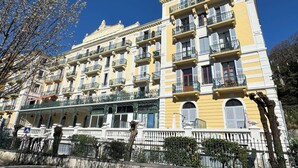 A multi-story building with balconies, a white facade, and a clear blue sky.