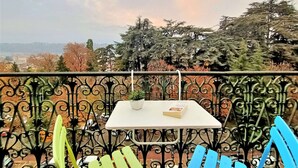 A balcony with a table and chairs, overlooking a cityscape and trees.