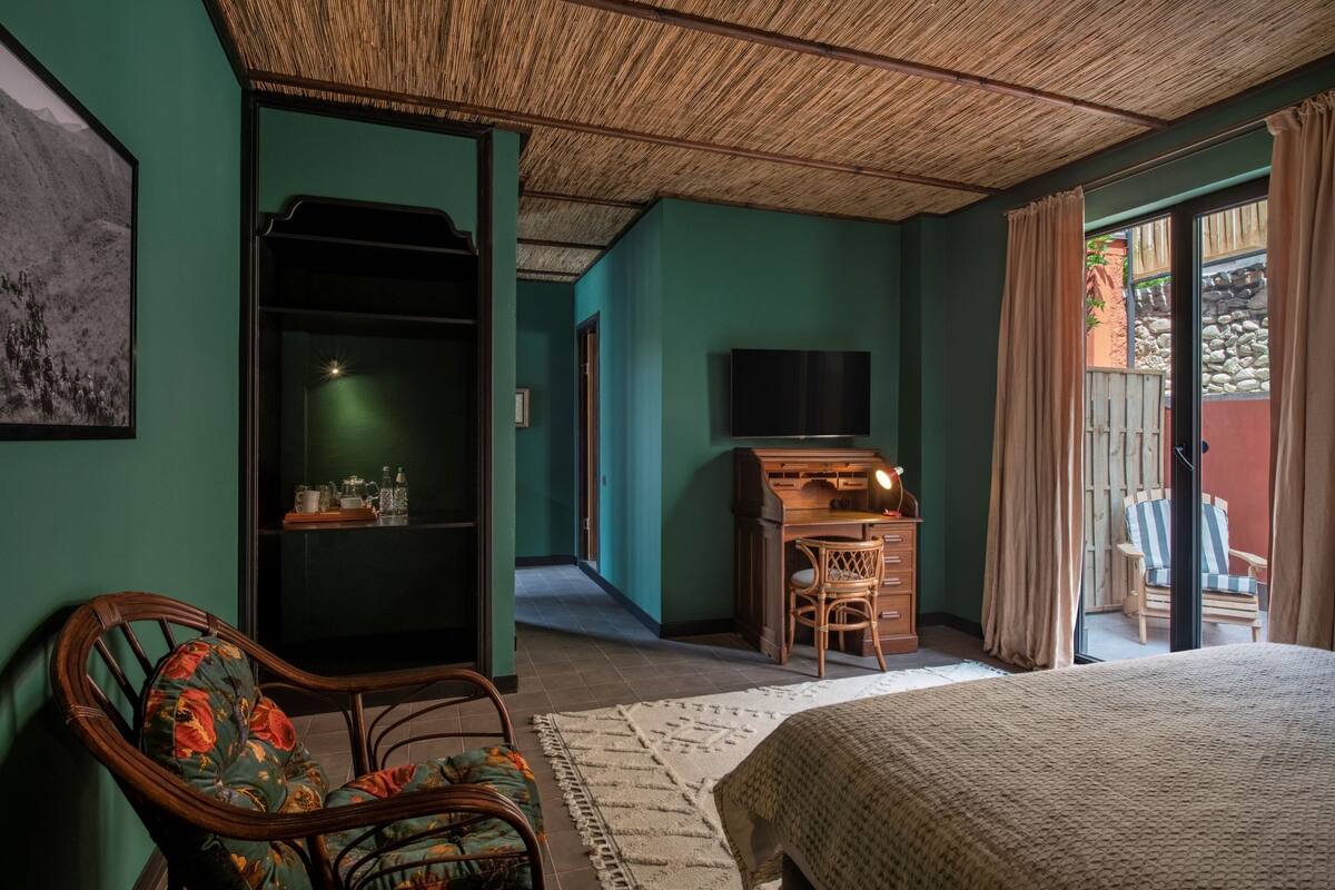 A room with a bed, a desk, a television, a wardrobe, and a chair.