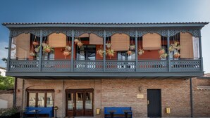 A building with a balcony, hanging planters, and outdoor seating.