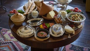 A round wooden table with various food items and utensils, including cheese, bread, and vegetables.