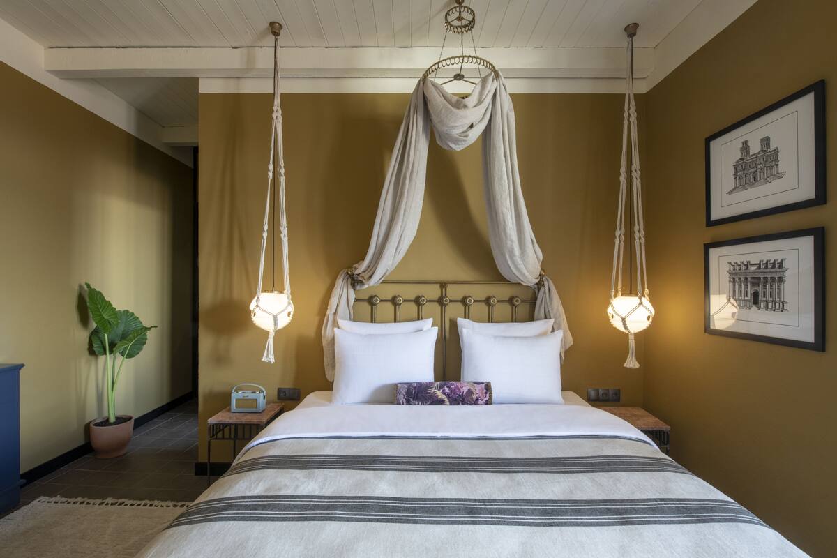 A hotel room with a large bed, a canopy, and two wall-mounted lamps.