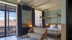 A bedroom with a bed, a sofa, a small table, and a balcony with a chair.
