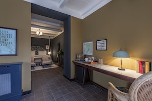 Ein Hotelzimmer mit Essbereich, einem Schreibtisch mit Lampe und gerahmten Bildern an der Wand.