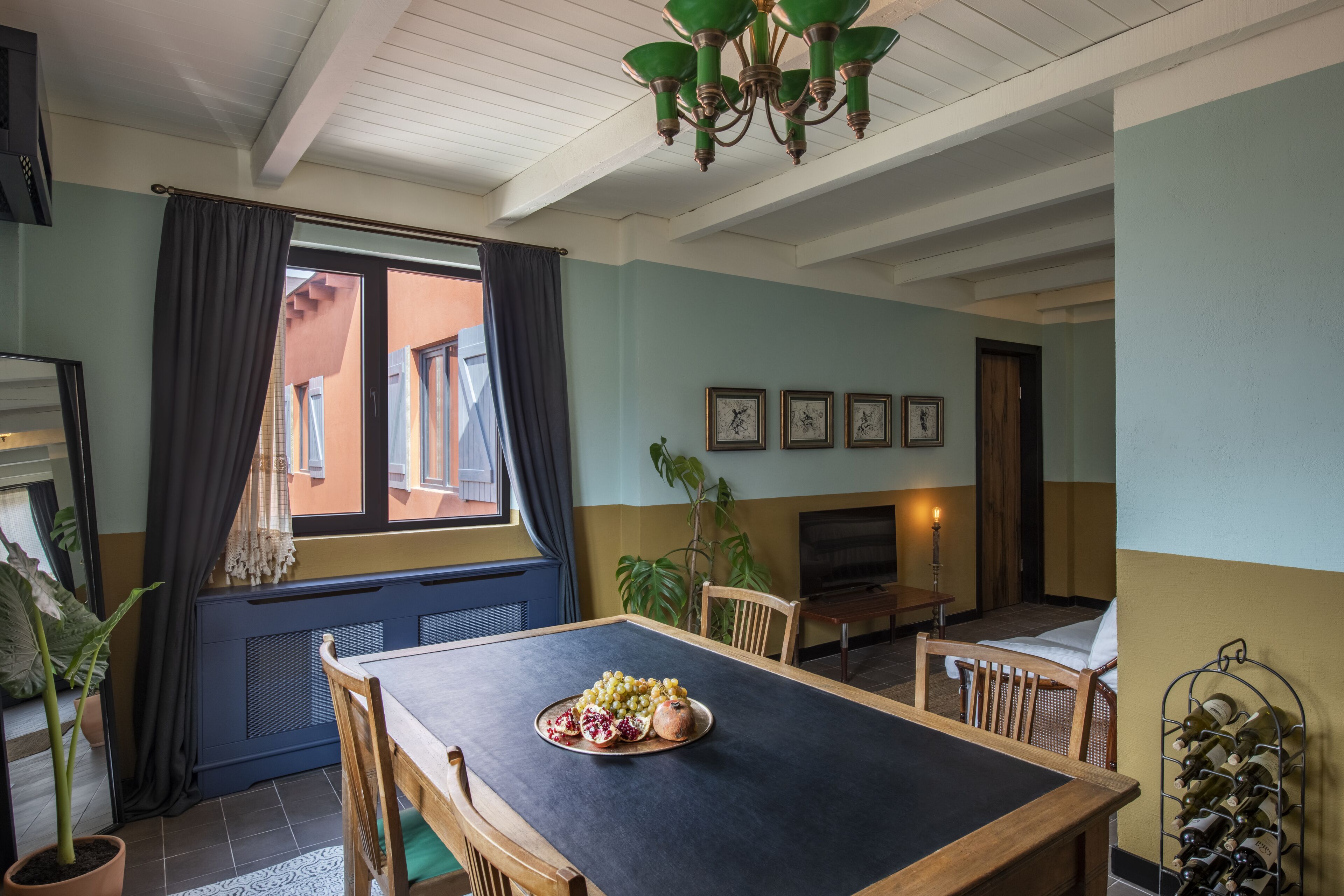 Spisestue med et bord dækket til to, en lysekrone og et vinskab.