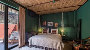 Un dormitorio con una cama grande, una lámpara colgante, una silla y vistas al exterior.