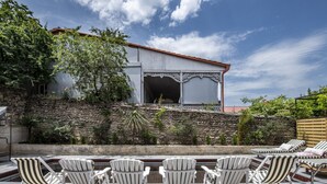A patio with white Adirondack chairs and a stone wall.