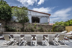 A patio with white Adirondack chairs and a stone wall.