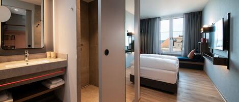 Een moderne hotelkamer met een grote spiegel, een bed, een televisie en uitzicht.