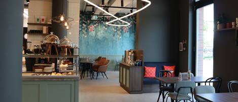 Een modern caféinterieur met een balie, zitgedeelte en decoratieve muur.