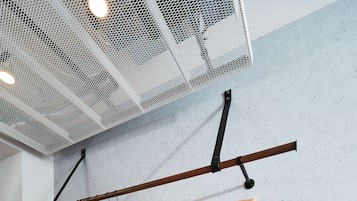 Ett rum med en bänk, en hängande klädställning, en anslagstavla på väggen och en brun väska på golvet.