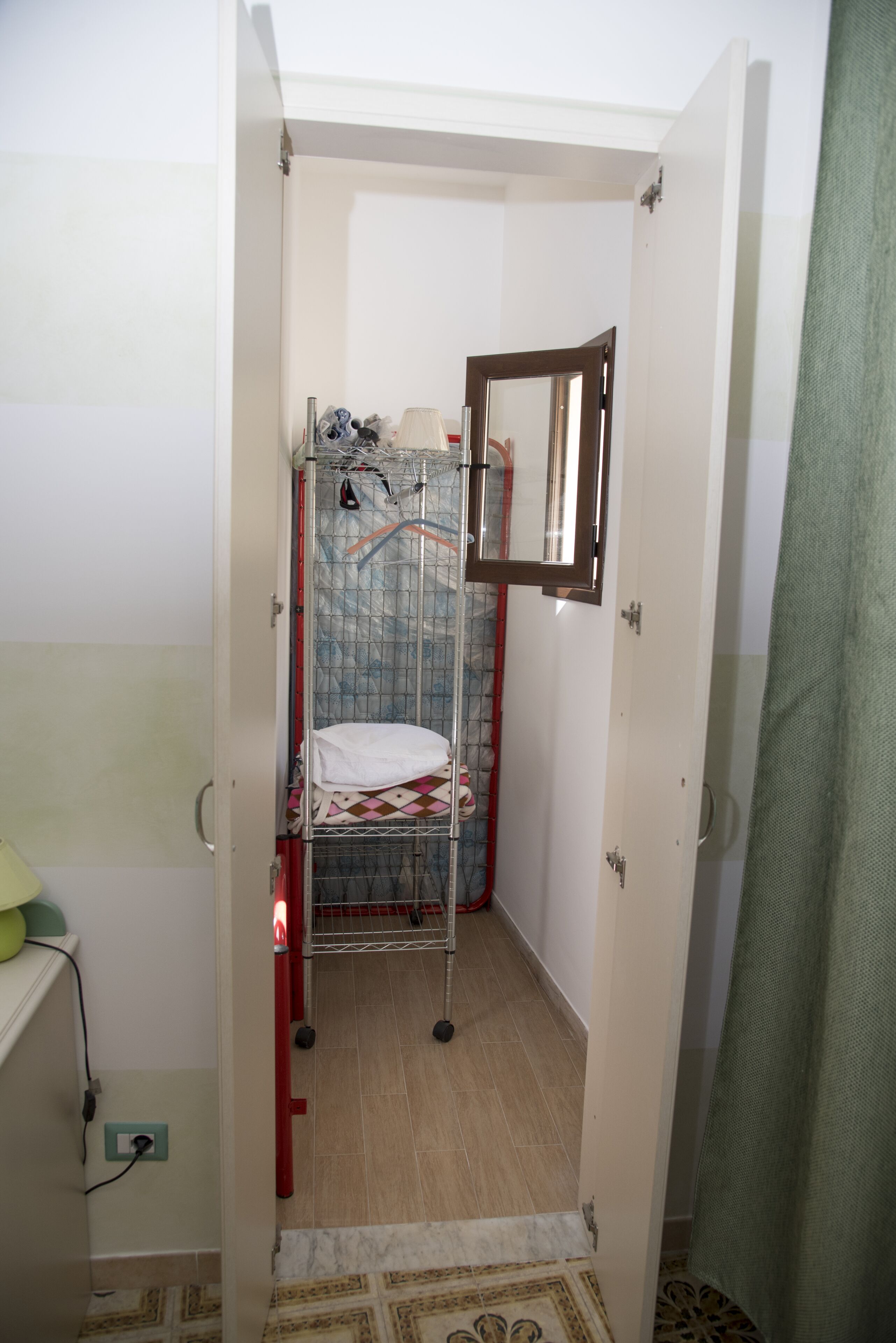 Une petite salle de bain étroite, avec une cabine de douche, un miroir et un porte-serviettes.