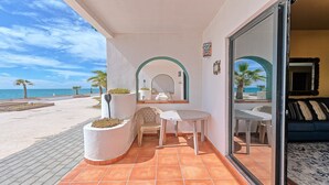 Ein Balkon mit Meerblick, ein Sessel, ein kleiner Tisch und eine Couch.