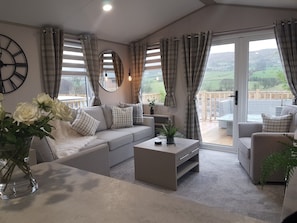 A modern living room with a grey sofa, a coffee table, and a large window with curtains.