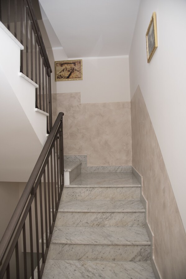 A staircase with marble steps, a wooden handrail, and beige walls.