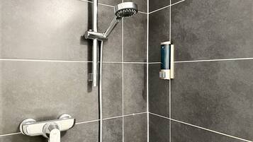 Ein Badezimmer mit Dusche, Duschbrause und Wandseifenspender.