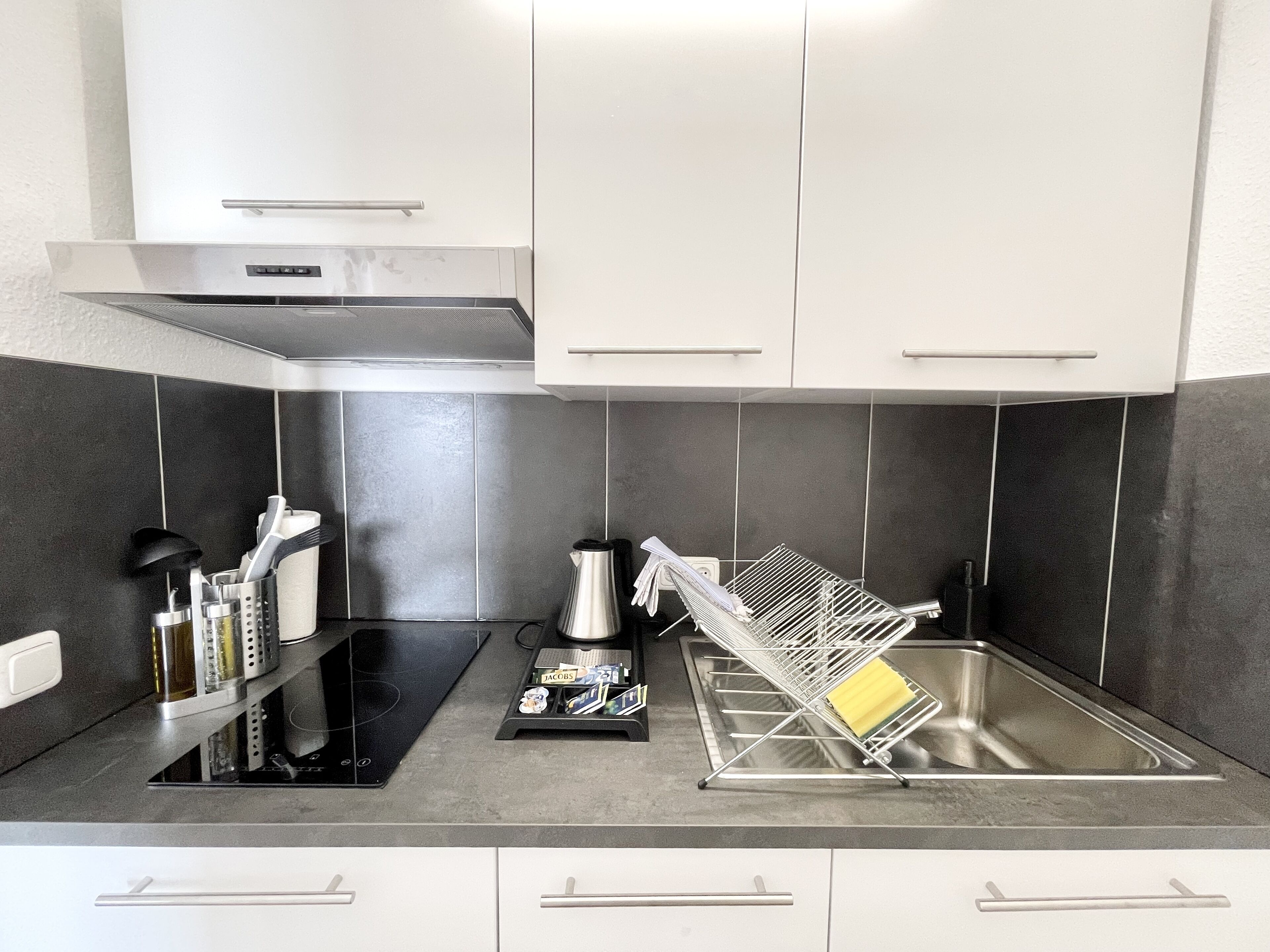 A modern kitchen with a black countertop, white cabinets, and a stainless steel sink.