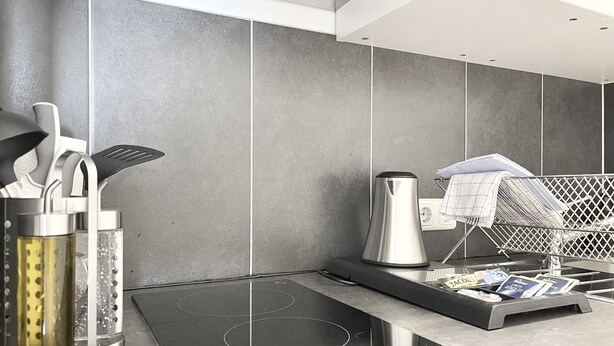 A modern kitchen with a built-in induction cooktop, a kettle, and a utensil holder.