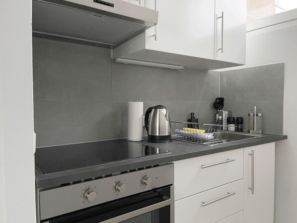 A modern kitchen with stainless steel appliances, a kettle, and a dish rack. - Zentral gelegene Studios (Osnabrueck)