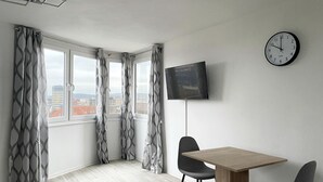 A modern room with a large window, a flat-screen TV, and a wooden table with two chairs.