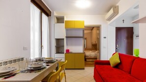 Un espacio habitable compacto con comedor, kitchenette, sofá rojo y cama.