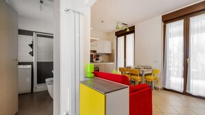 Un apartamento moderno con cocina, comedor y un sofá rojo.