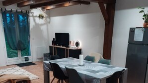 Un coin repas avec une table dressée pour quatre personnes, un téléviseur et un réfrigérateur.