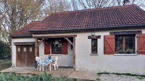 Une maison avec un toit en tuiles, une véranda avec une table et des chaises, et une fenêtre avec des volets.