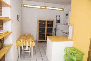 A compact kitchen with a dining table, chairs, and a cabinet.