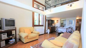 Ein Wohnzimmer mit einer Couch, einem Fernseher und einem Essbereich mit Stühlen und einem Tisch.