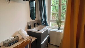 A bathroom with a sink, mirror, and a window with curtains. - L'annexe du Château de Saint Genix (Saint-Genix-les-Villages)